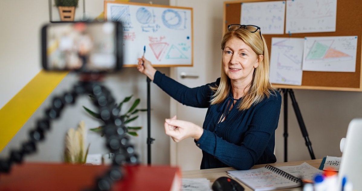 A woman records herself teaching.