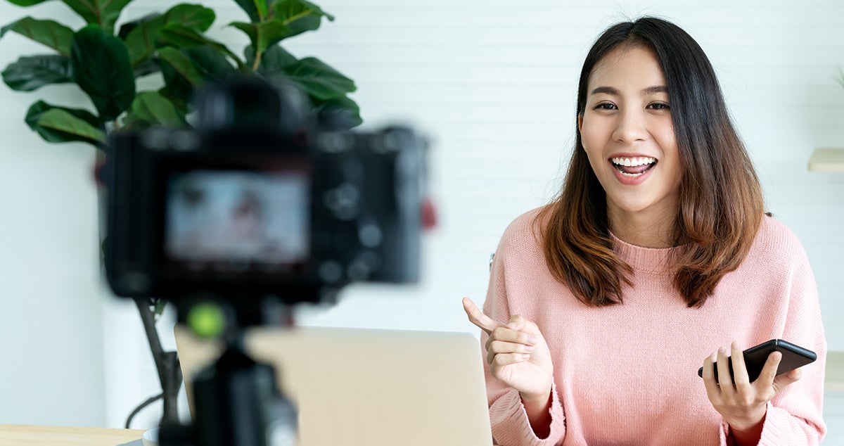 A woman speaks to a recording camera.