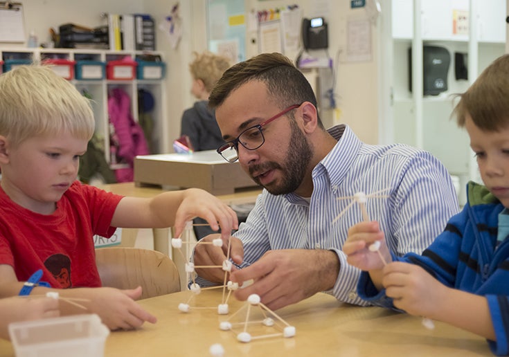 Photo of teacher with children at a table building a marshmallow and toothpick molecule model