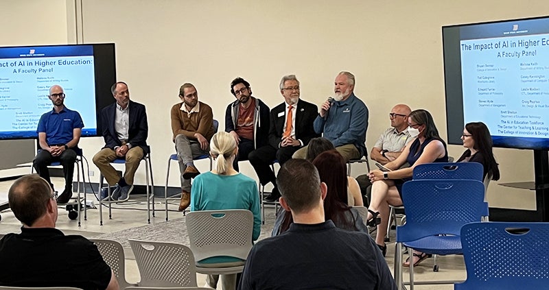 Panel of speakers seated at the front of a room