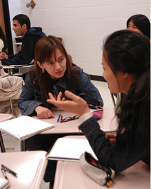 Student and teacher talking desks pulled close together