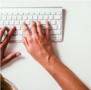hands typing on a white keyboard