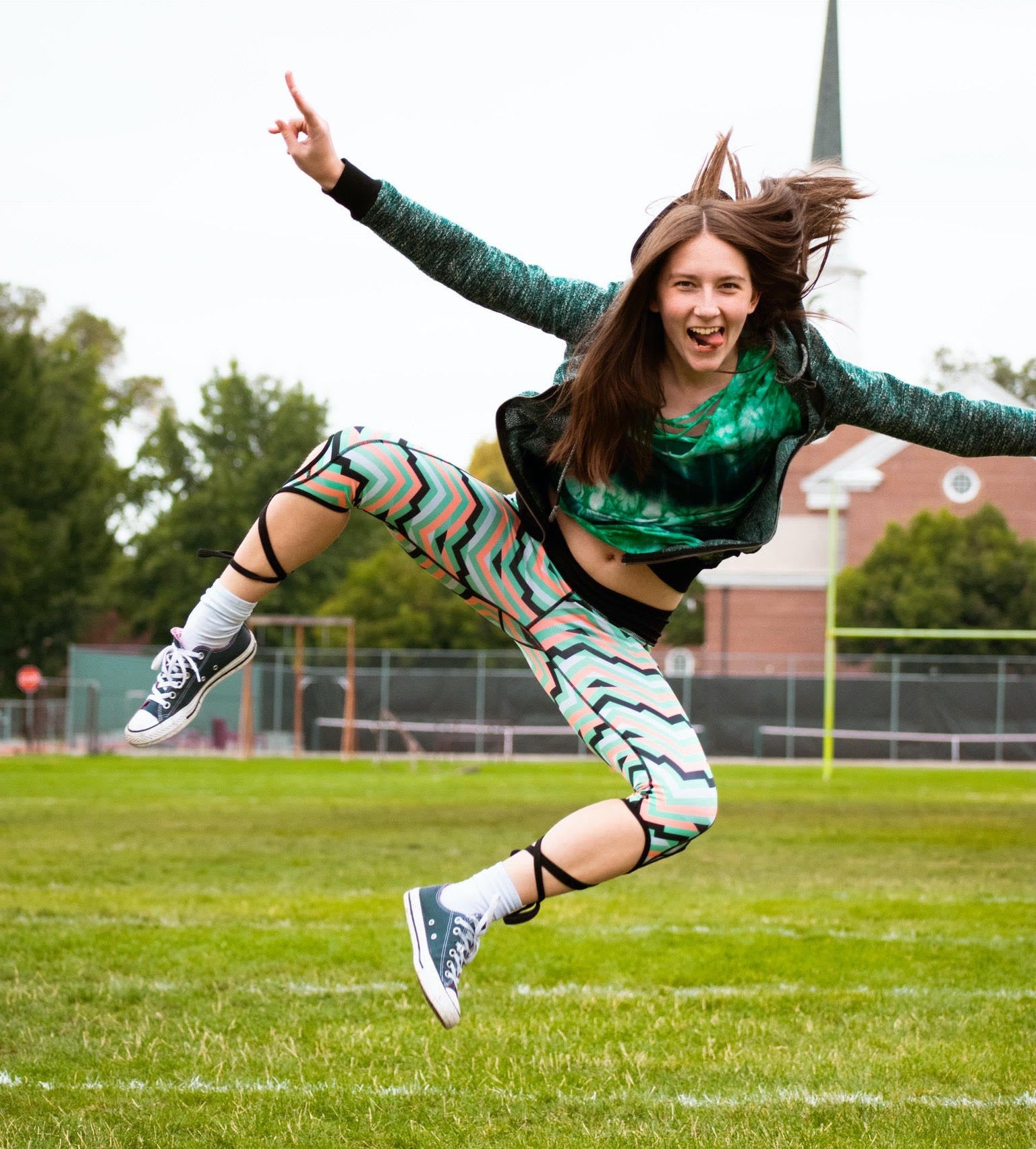 Mary Brown jumping mid-air with arms & tongue out