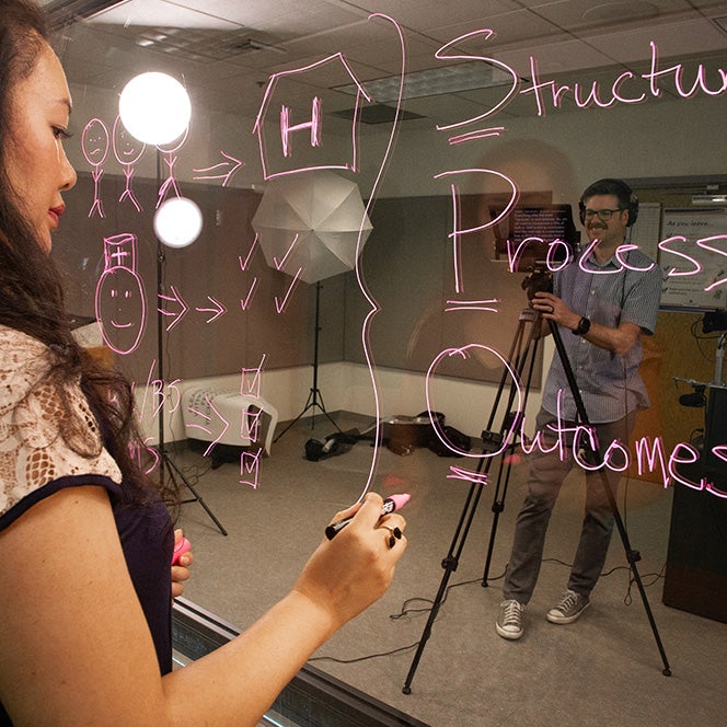 Woman writes on glass board