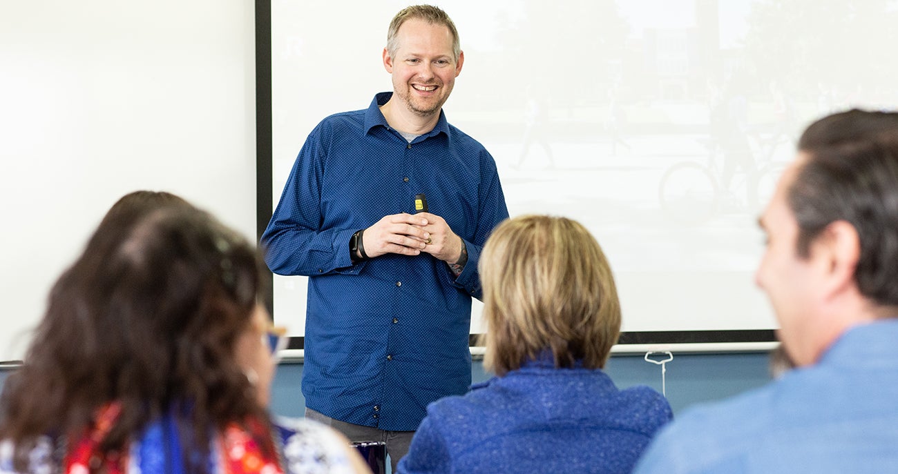 Jeremy Graves at the front of a classroom, smiling.