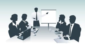 A sillhouette image of people sitting at a conference table having a meeting