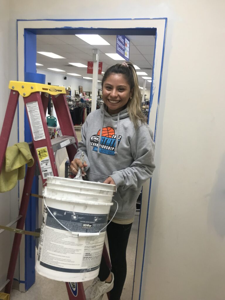Student holding a bucket full of painting supplies