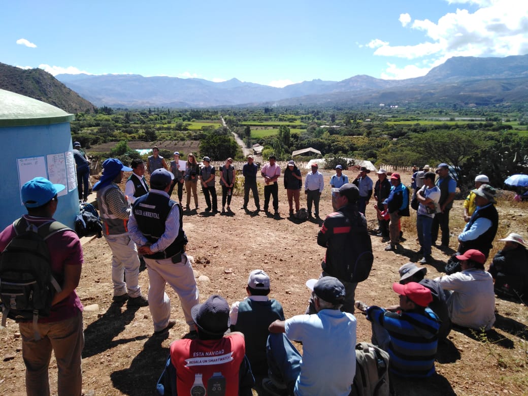 A group of people in a circle listening to a presentation. 