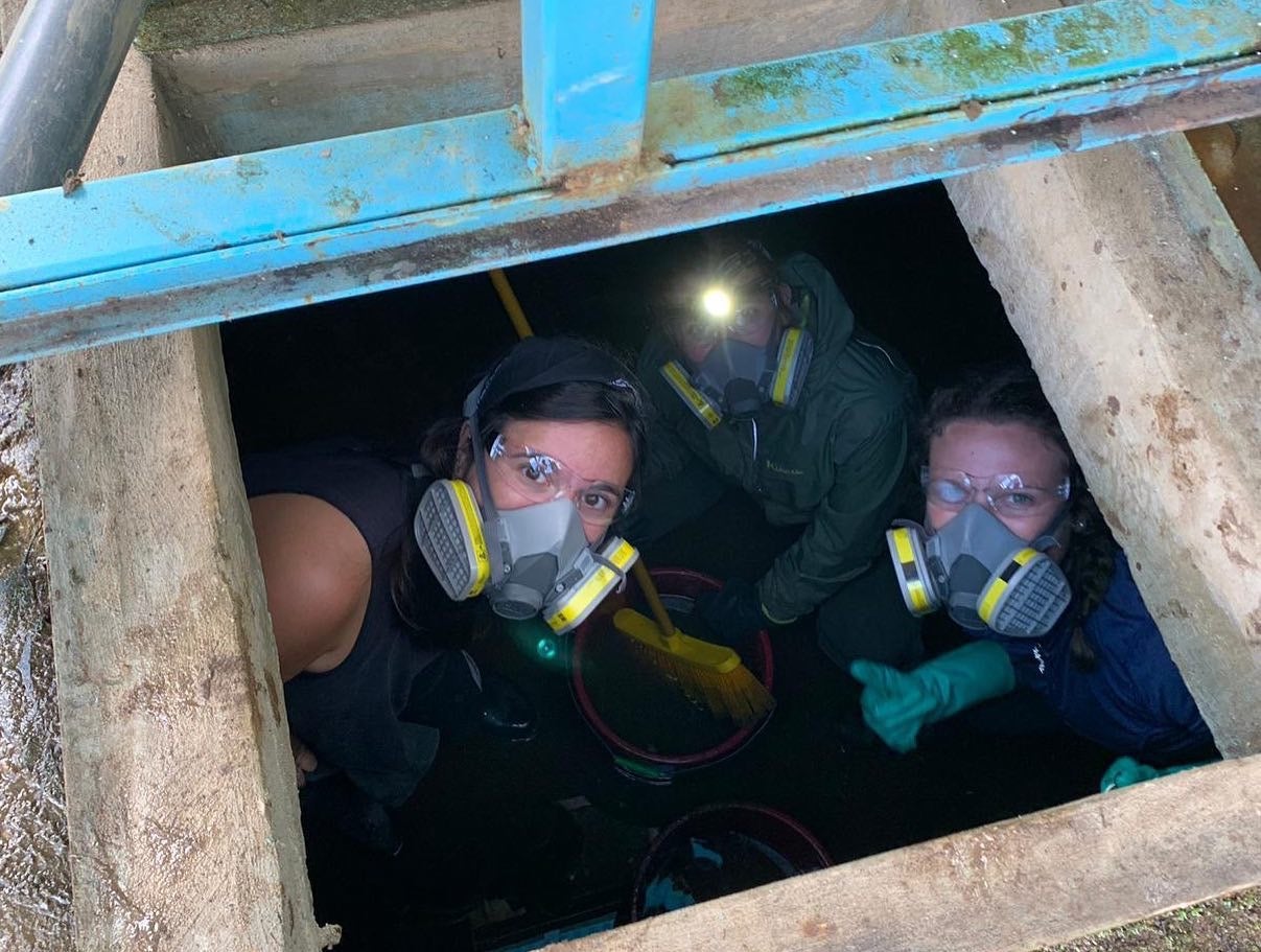 Emma and two others wearing masks inside a hole below ground. 