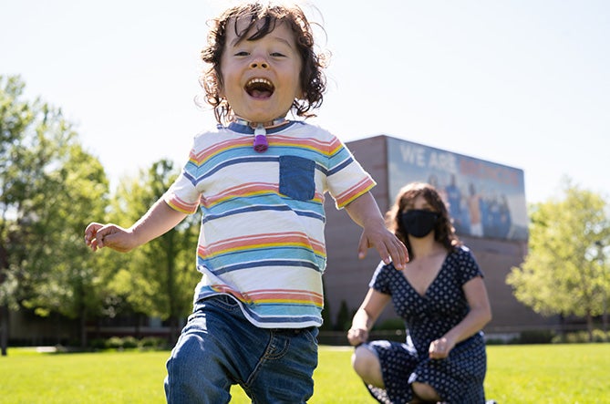 Emma's son runs toward camera smiling with Emma watching in background