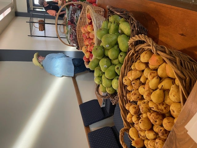 Baskets of pears and apples line a table at a food pantry.