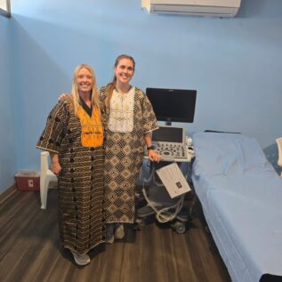 Hall and Tracy in traditional wear that they were gifted thanks to their efforts.