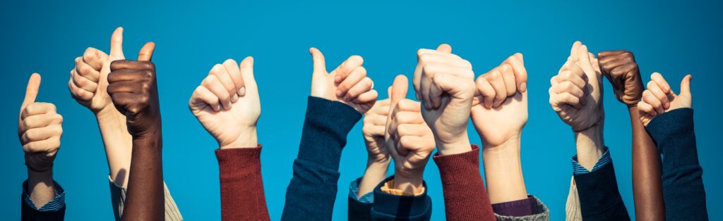 Multiracial Thumbs Up Against Blue Sky