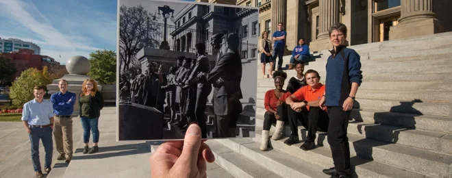 A person holds up a historic black-and-white photograph that aligns perfectly with the background, showing the same building steps in the past and present