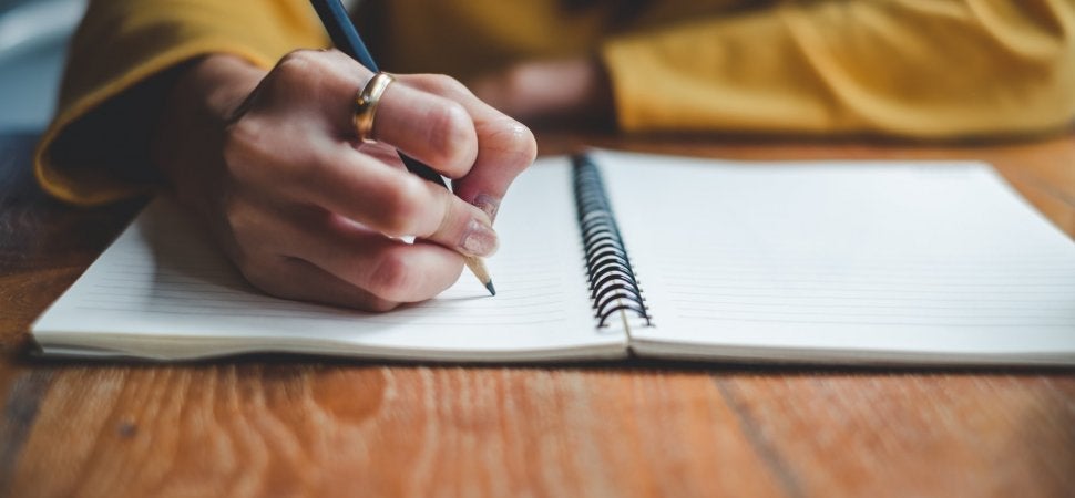 A close up image of a student writing on a notepad