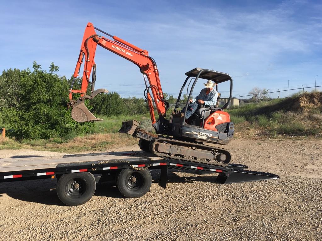 a red tractor backs down off of a trailer