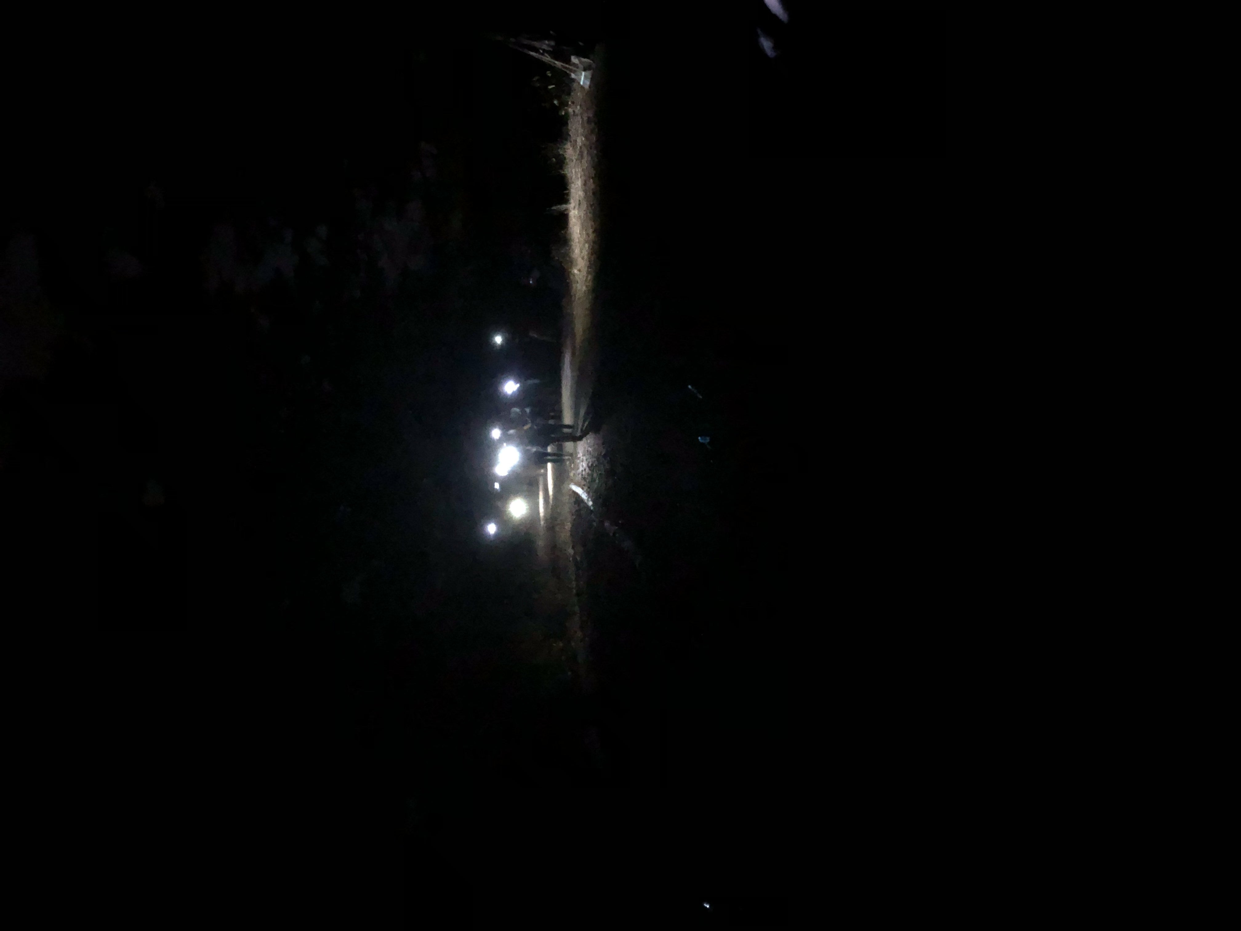 people with head lamps on, walking through the darkness