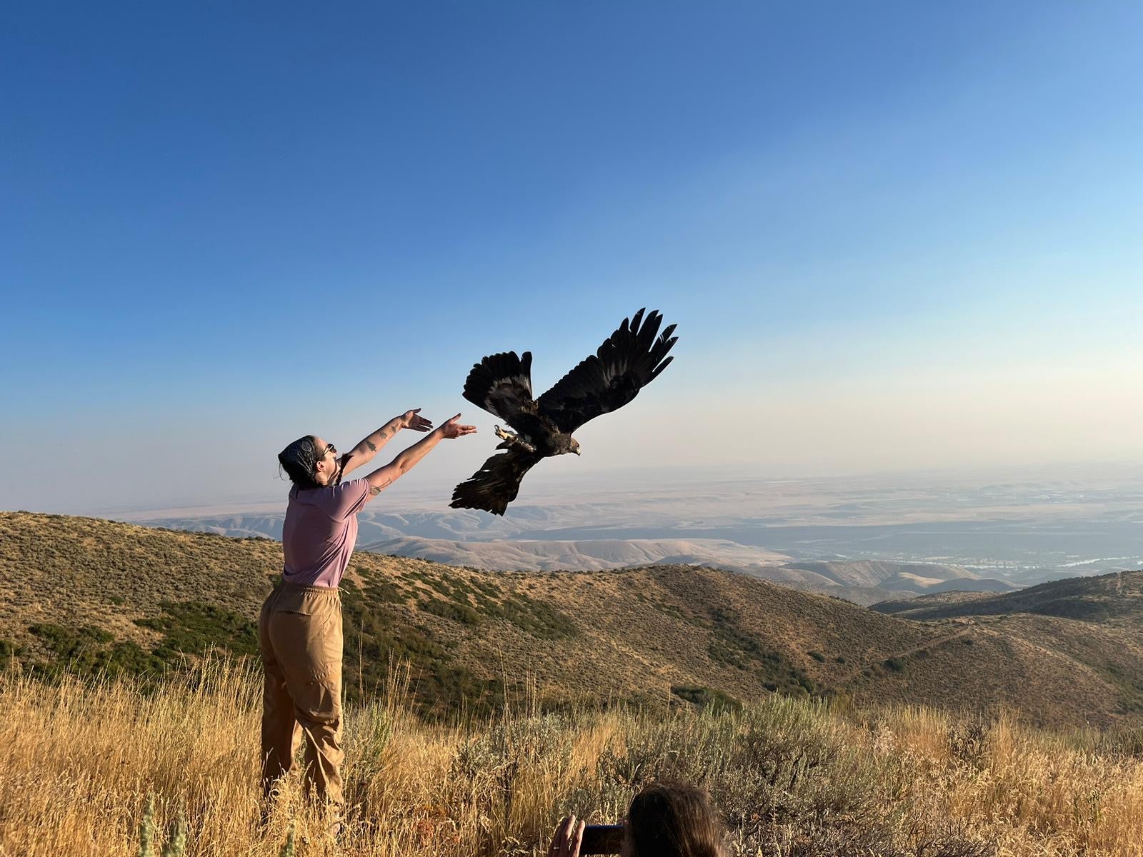 Hannah stands with arms stretched out. The photo is snapped just as the eagle spread its wings to take flight from Hannah's arms.