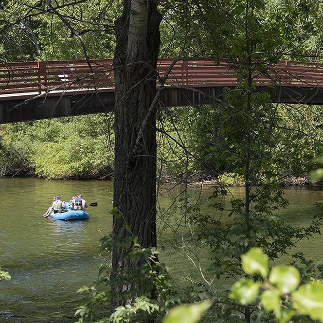 People in a raft, floating on the river under a bridge