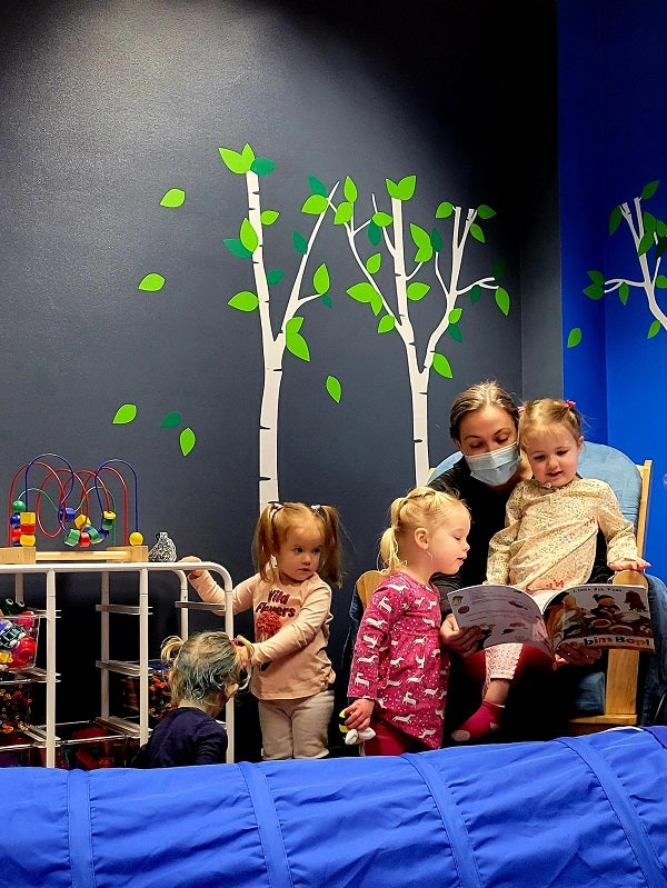 Photo of librarian Kelsey reading a book to children