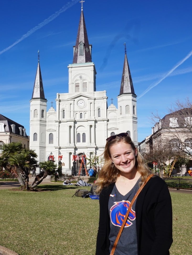 young woman standing in frong of white church building in Europe