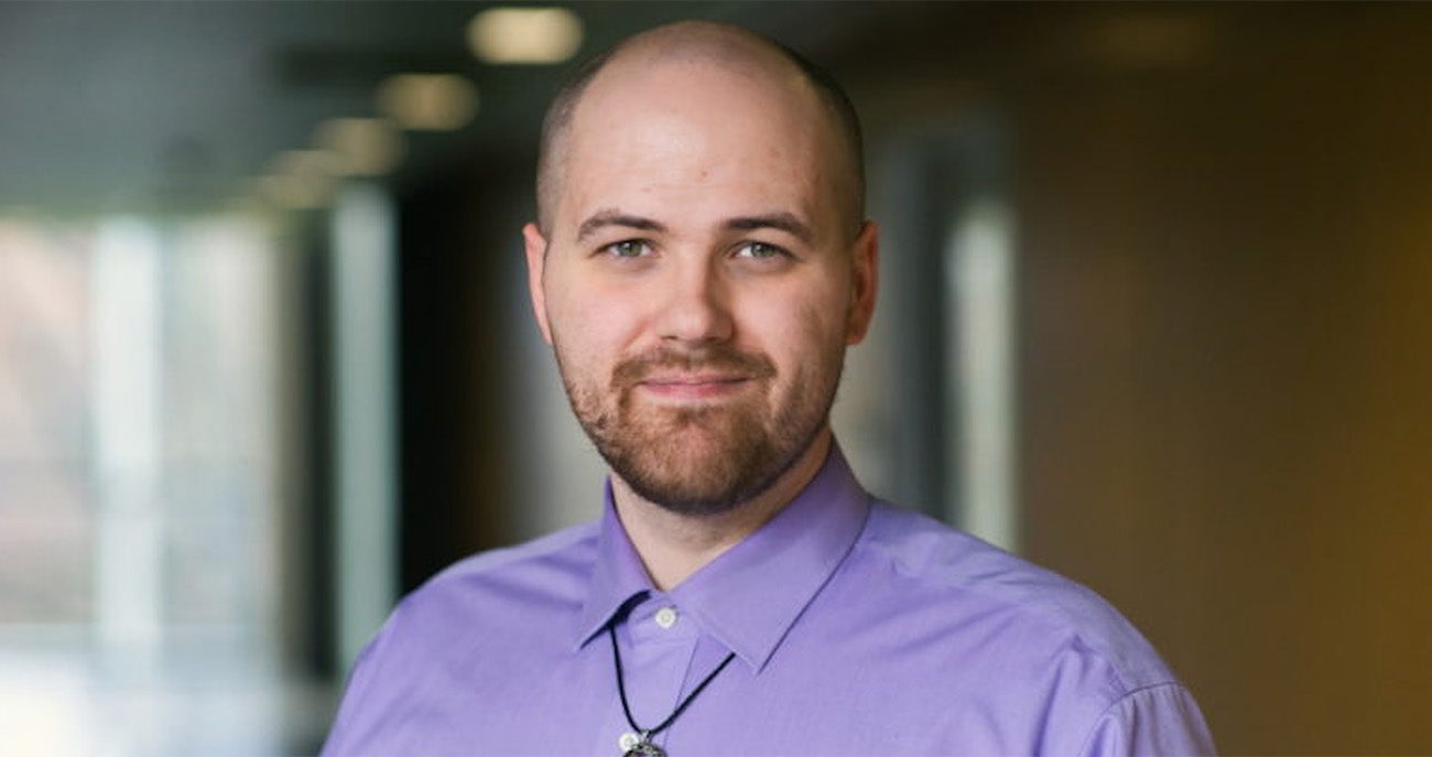 alumnus Curtis-Green-Eneix appears in a lavender dress shirt standing in a hallway