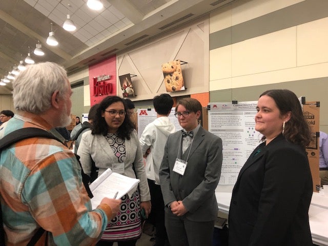 Students and faculty viewing a poster
