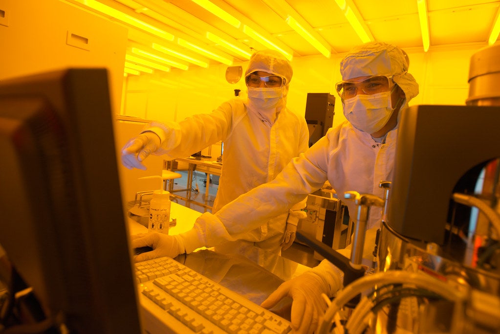 Two people fully gowned in a lab