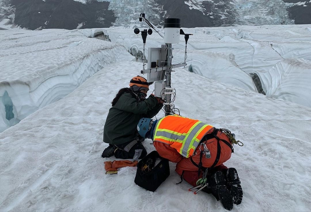 two people install weather in glacier ice