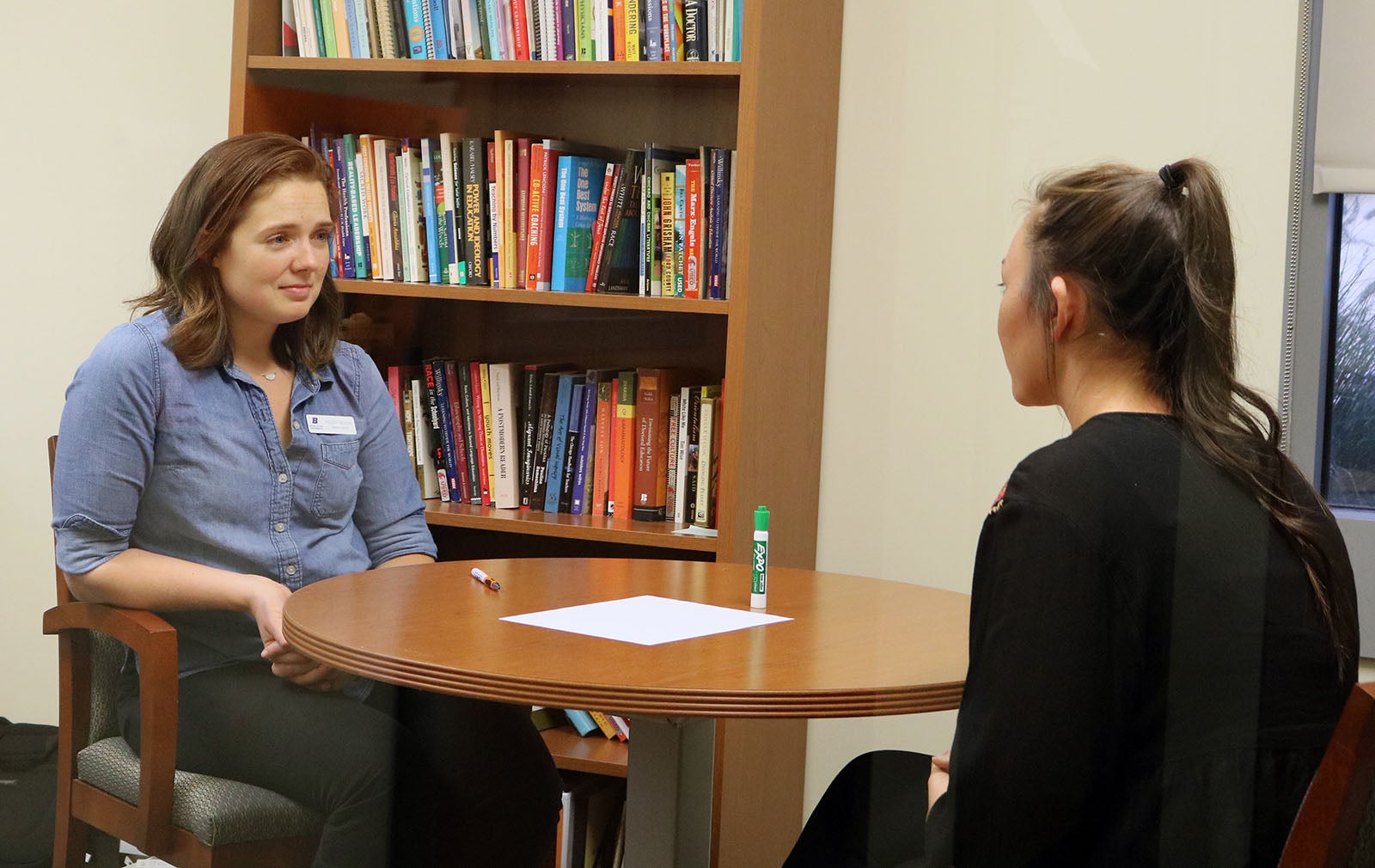 Kelsey sits at a table with a student