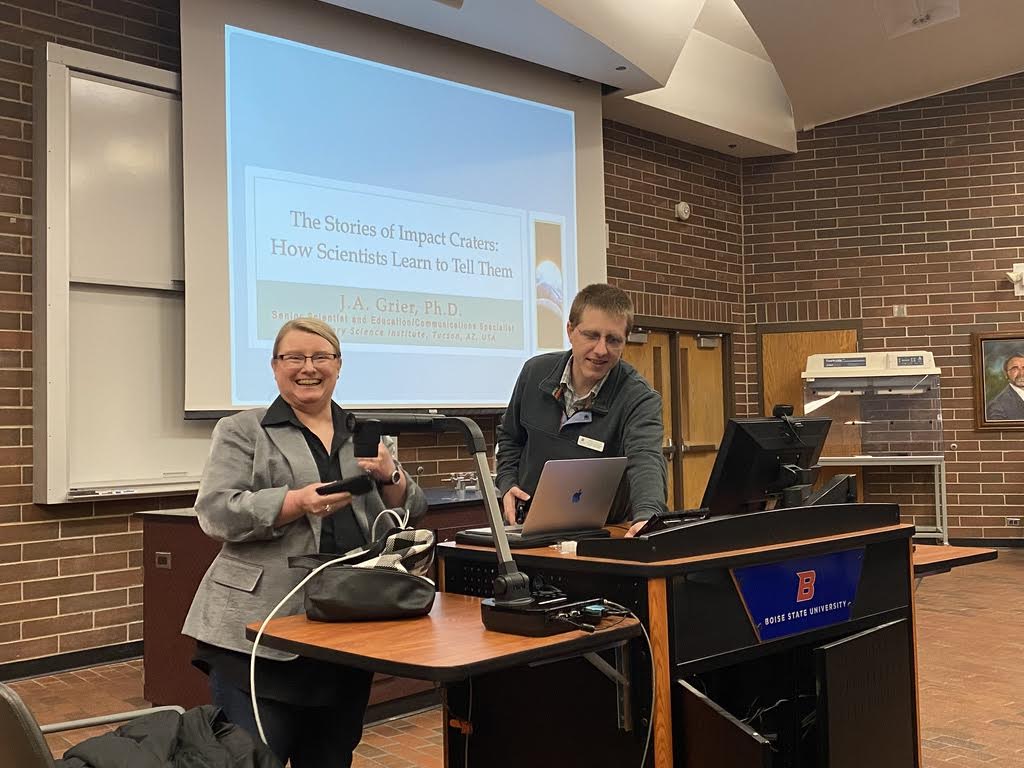 two people stand in front of presentation screen