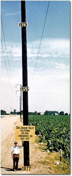 Joseph Poland shows the high rate of subsidence next to a power pole and field.
