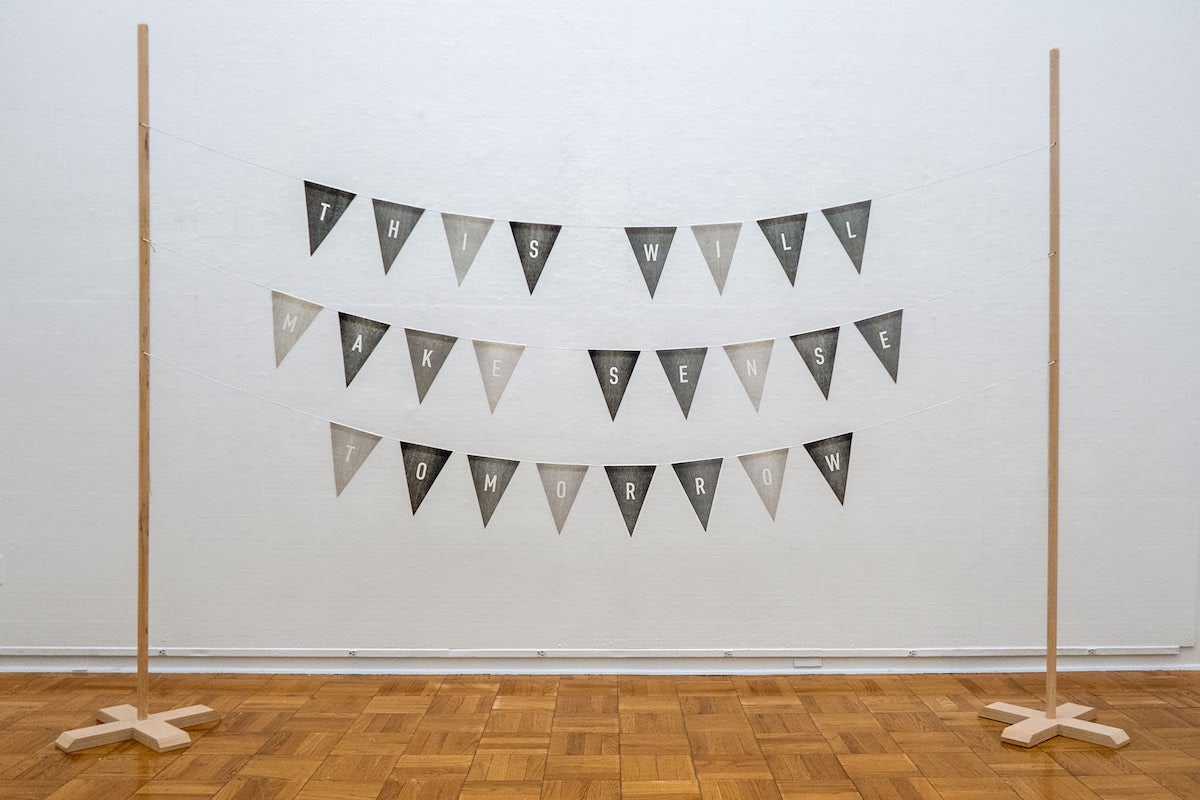 Wood relief printed triangles hung to display "This will make sense tomorrow." 