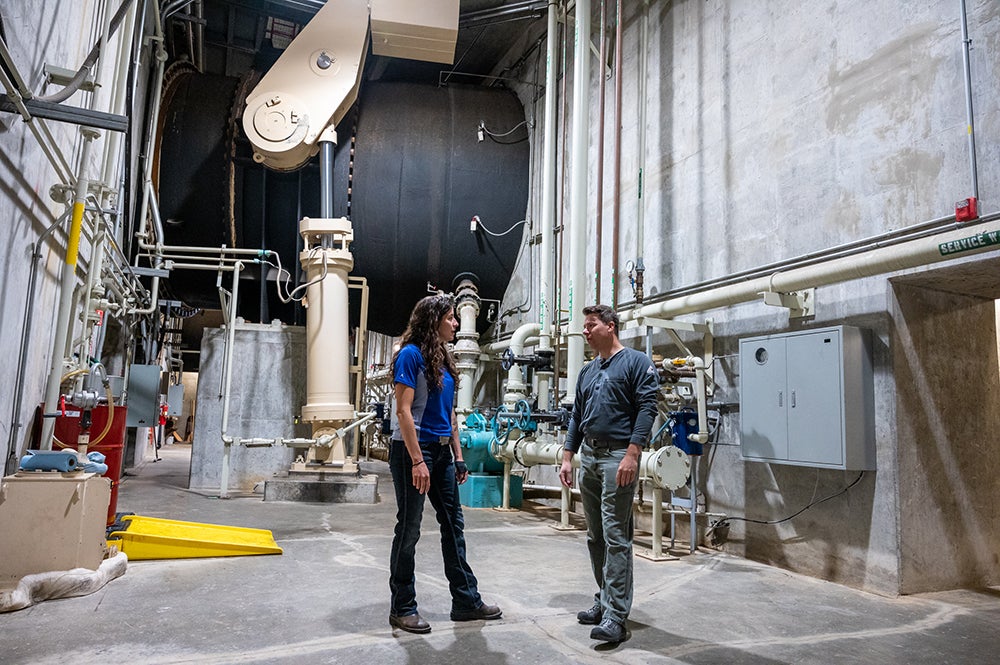 two people stand inside hydro dam power plant