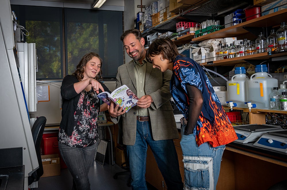 Elise Overgaard, Allan Albig, and Roxy Albig look through book.