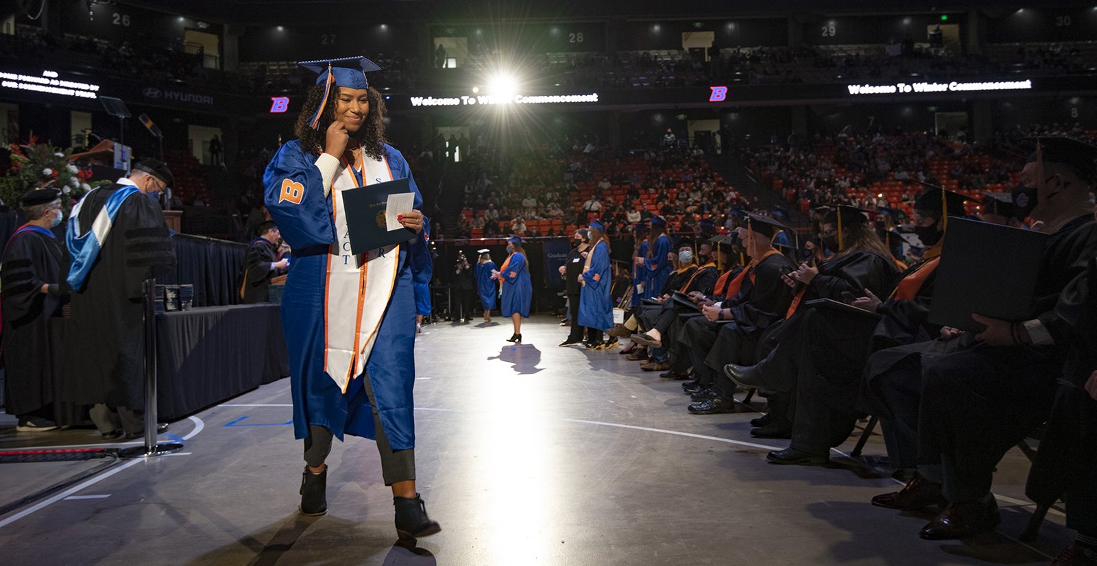 A student crosses stage at the winter commencement. 