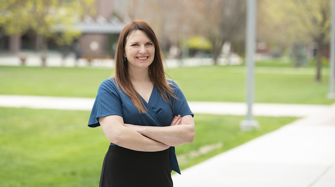 Kara Fink stands on the quad, arms crossed and smiling