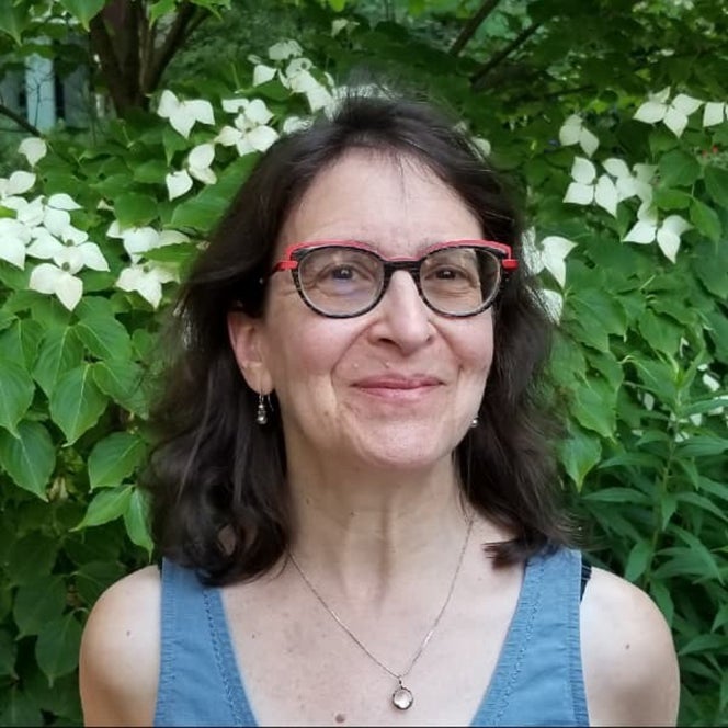 Susan Blum standing outside in front of a flowering tree