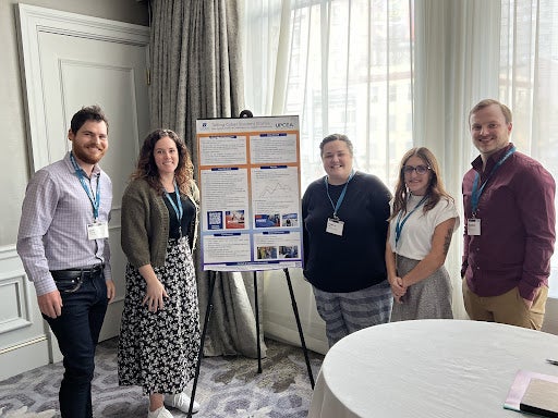 A group of people stand in front of a poster 