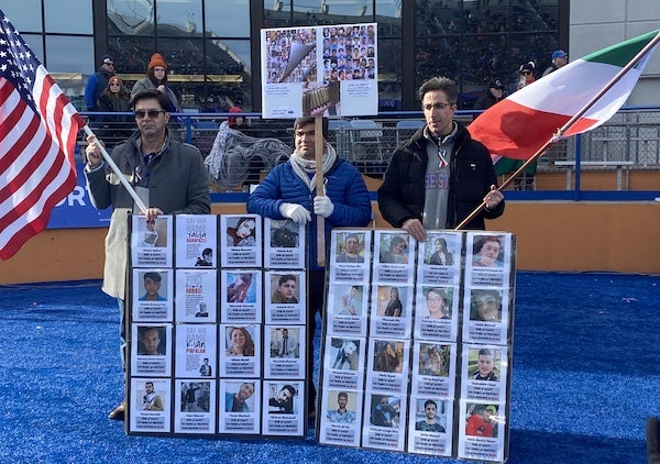 Persons on a field holding Iran and US flags