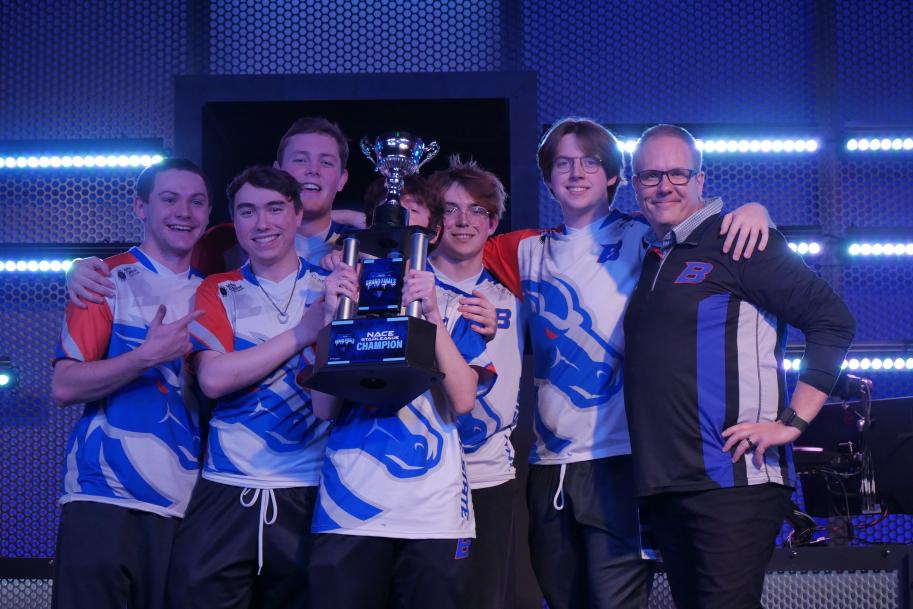 Head coach Doc Haskell poses with the Overwatch team after the team won the NACE national championship.