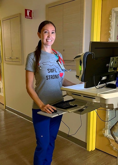 Jovita Gardner stands in scrubs at a computer for electronic patient records.