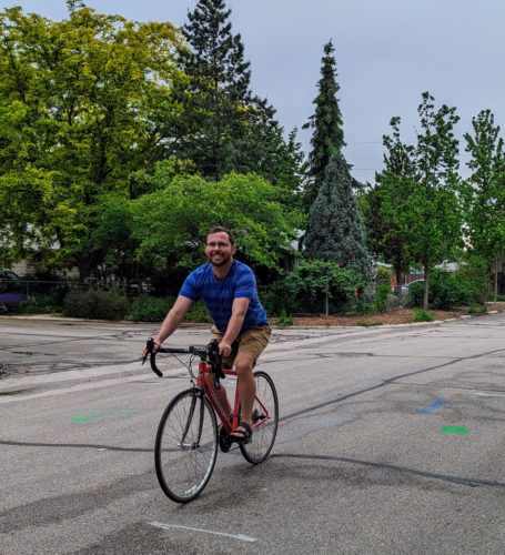 faculty member rides bike on road