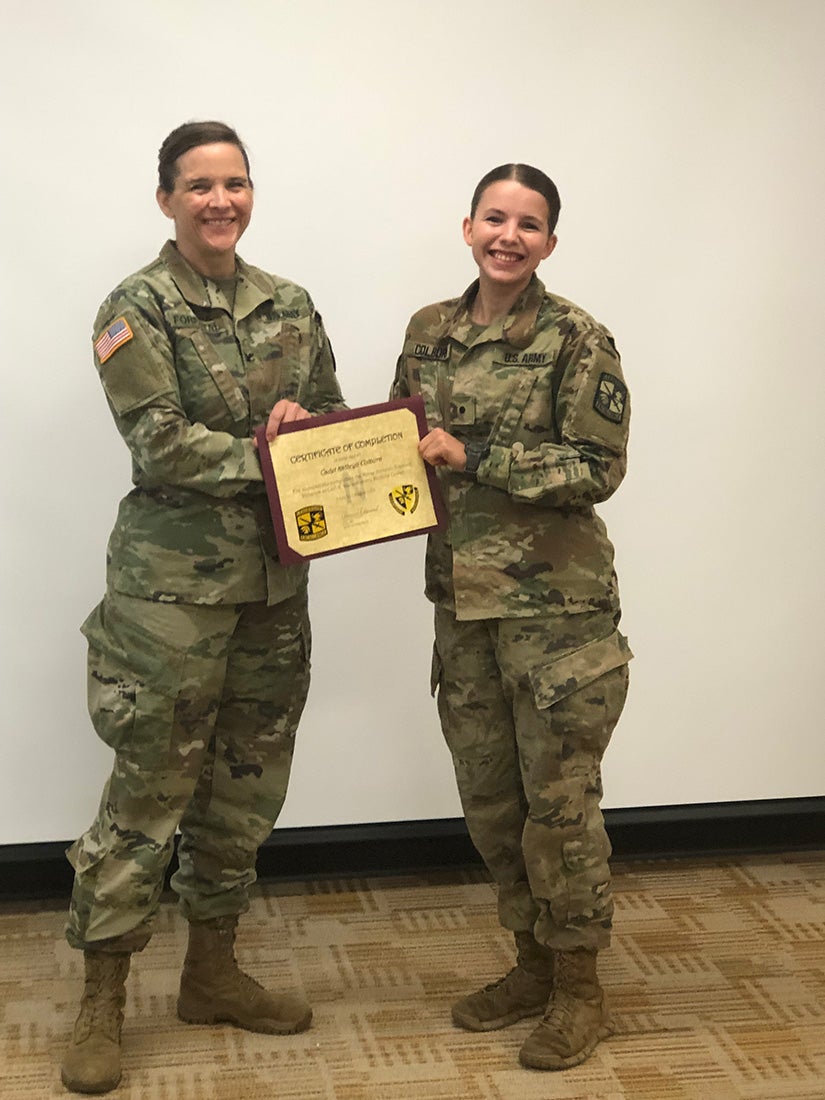 Colburn and a nurse officer in uniform stand holding a certificate.