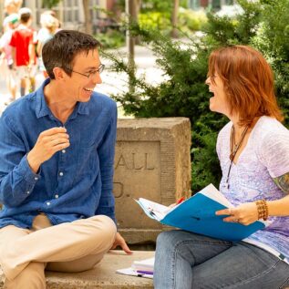 Man and woman sitting outside and laughing with each other.