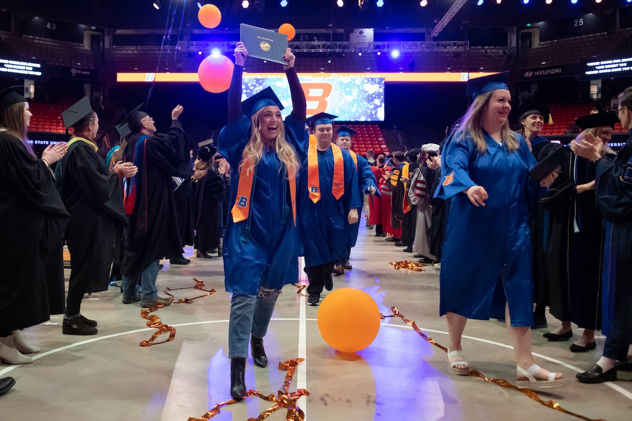A student holds a diploma cover at commencement.