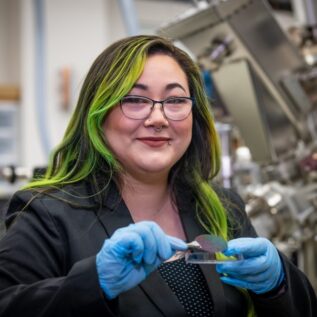 Icelene Leong holds a test wafer to measure semiconductor material electronic properties