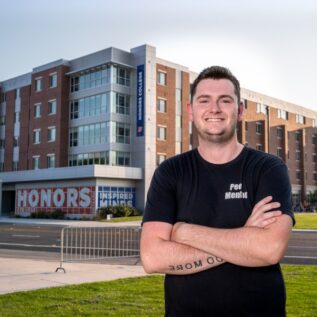 Ian Lambrecht posing in front of the Honors College.