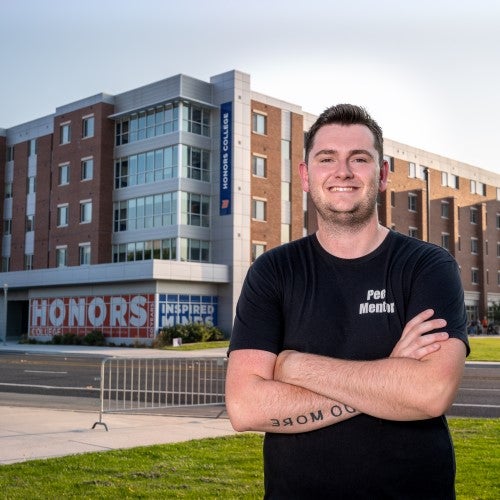 Ian Lambrecht posing in front of Honors College. 