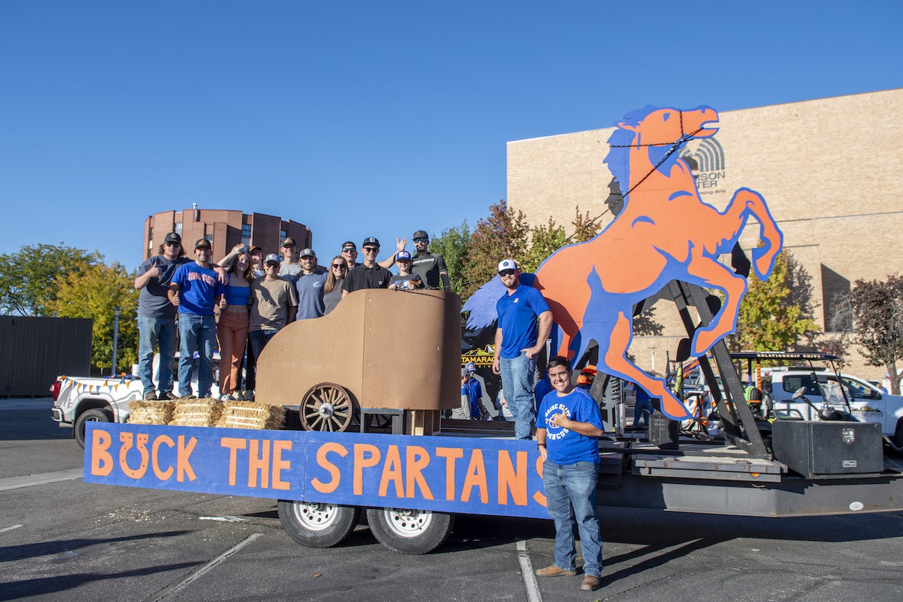 Persons pose with a float featuring a wooden horse and chariot